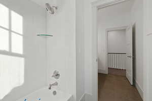 Full bath with washtub / shower combination and dark tile patterned flooring