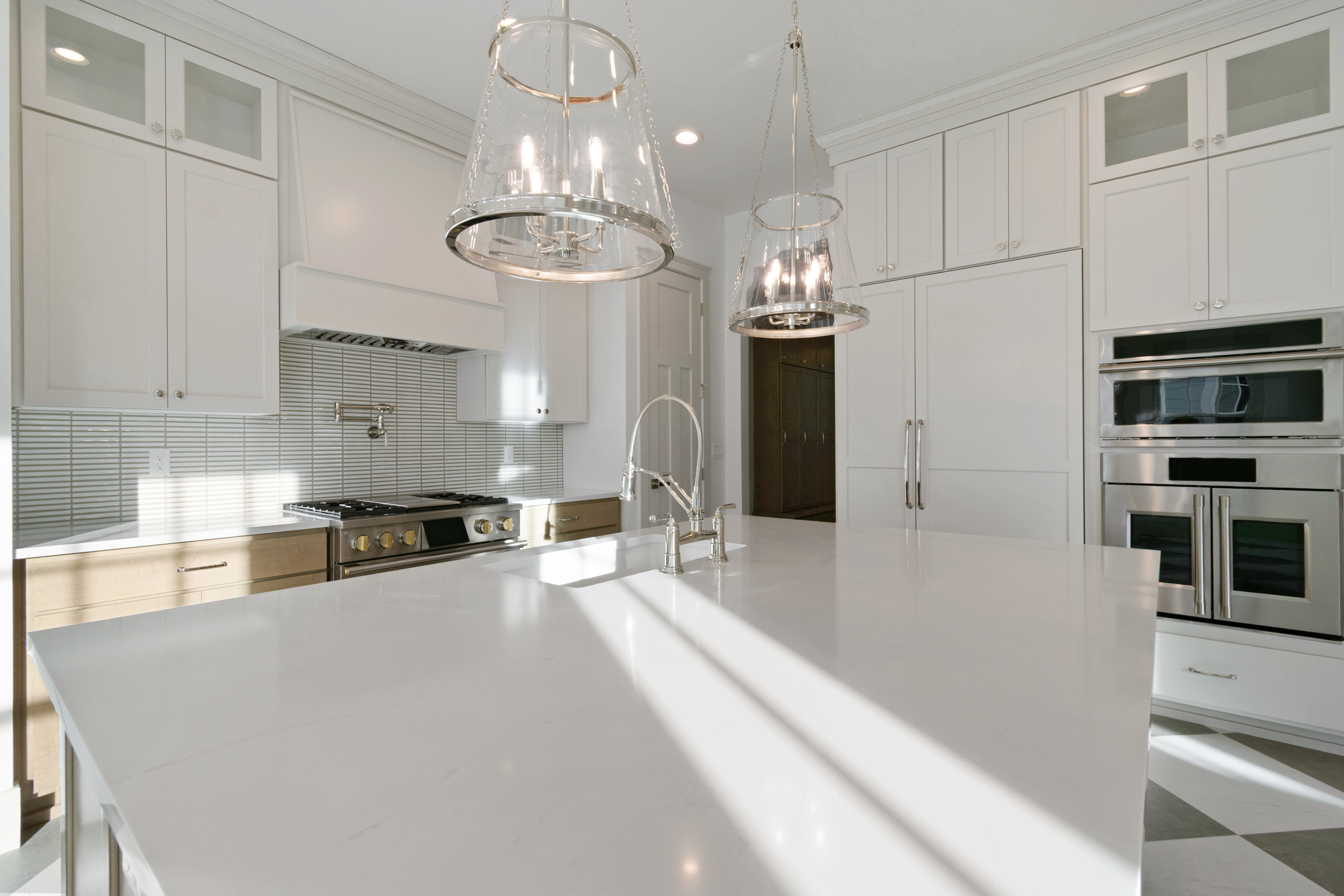 Kitchen with glass fronted cabinets, white cabinets, stainless steel appliances, and tasteful backsplash