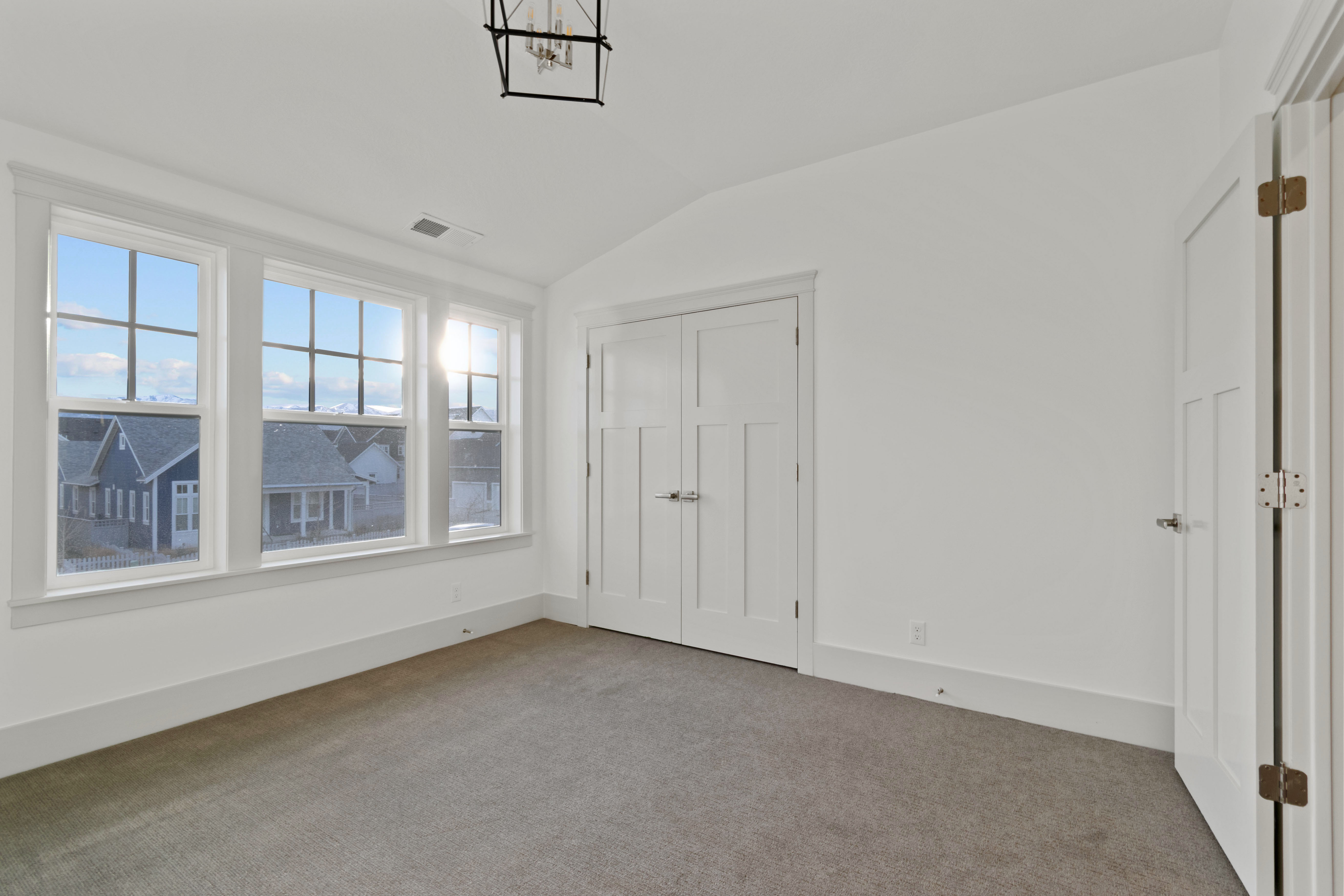 Unfurnished bedroom featuring vaulted ceiling, carpet floors, a closet, and suspended lighting