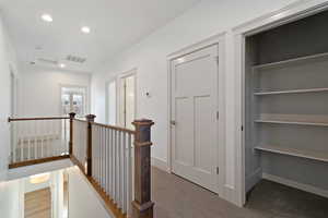 Hallway featuring an upstairs landing, recessed lighting, and light colored carpet