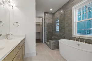 Full bath with a shower stall, a soaking tub, double vanity, a spacious closet, and recessed lighting