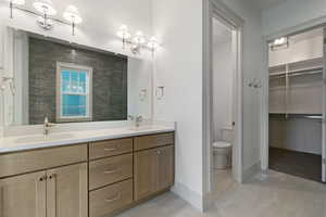Full bath with double vanity, a walk in closet, and light tile patterned flooring