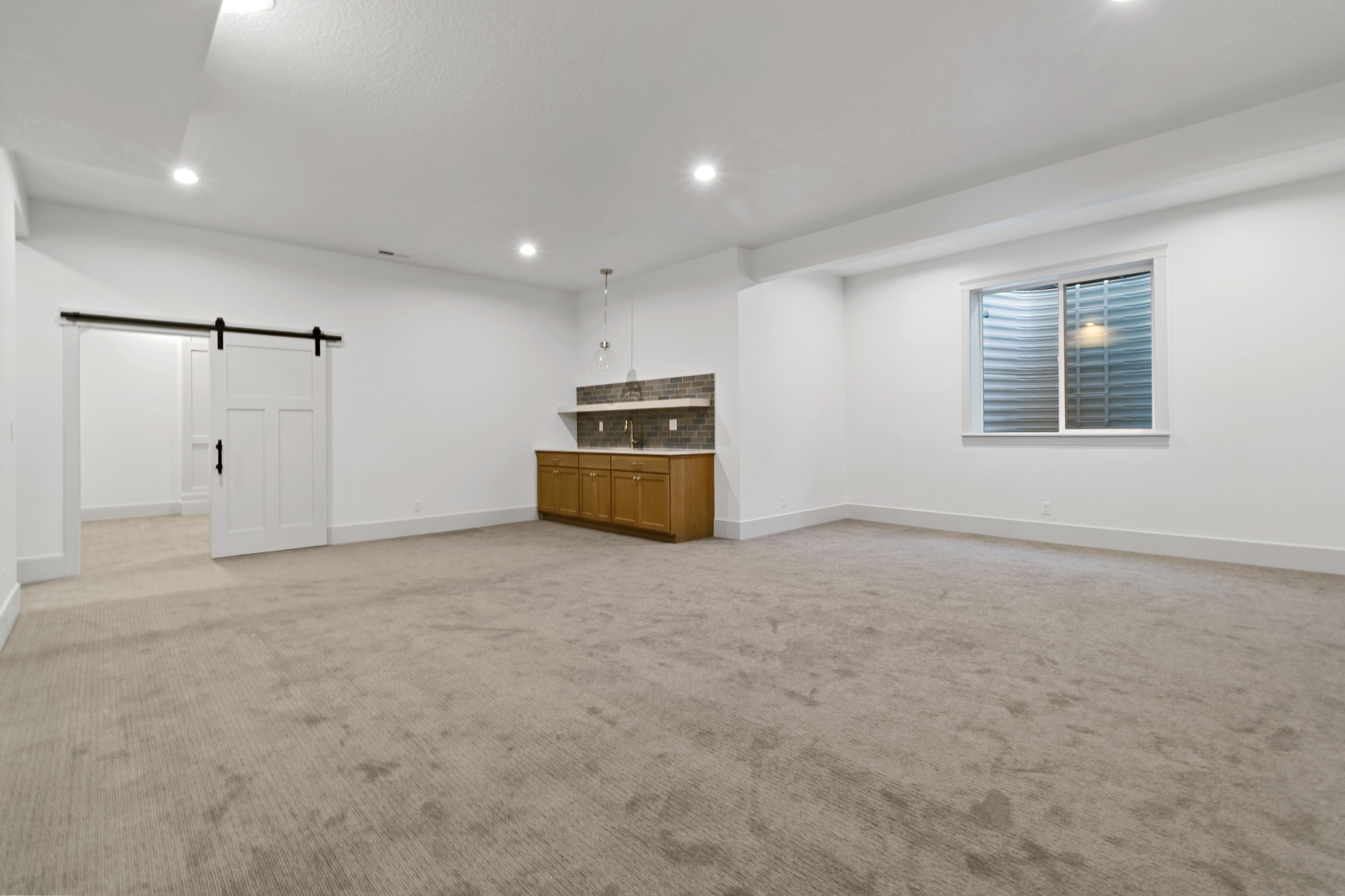 Basement featuring a barn door, light carpet, and recessed lighting