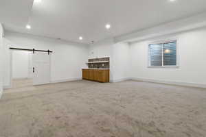 Basement featuring a barn door, light carpet, and recessed lighting