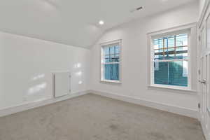 Additional living space with vaulted ceiling, light colored carpet, healthy amount of natural light, and recessed lighting