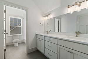 Full bathroom with double vanity, lofted ceiling, dark tile patterned flooring, and tub / shower combination
