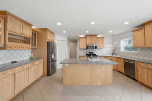 Kitchen featuring light wood finish cabinetry, a kitchen island, stainless steel appliances