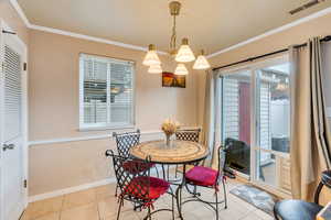 Dining space with crown molding, light tile patterned flooring, and hanging lights