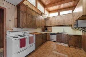 Kitchen with stainless steel appliances, light tile patterned floors, a wood ceiling with exposed beams, butcher block counters, and dark wood finish cabinetry