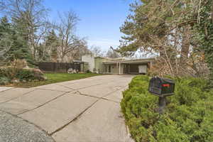 Mid-century inspired home featuring an attached carport, driveway, and stucco siding