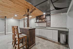 Indoor wet bar with wood ceiling, tasteful backsplash, recessed lighting, two tone cabinetry, and light countertops