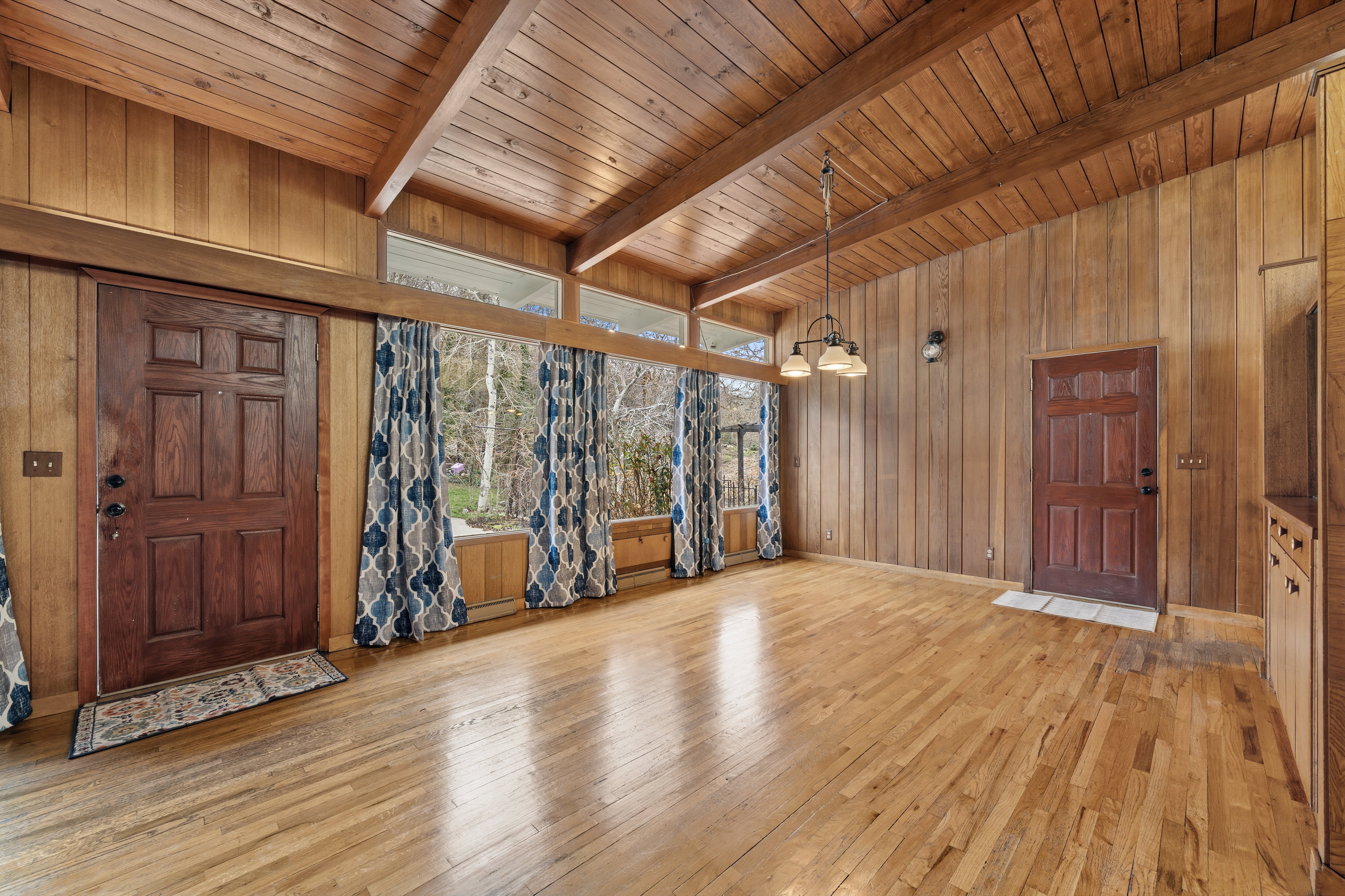 Foyer entrance featuring wooden walls, light wood-type flooring, a chandelier, wooden ceiling, and lofted ceiling with beams