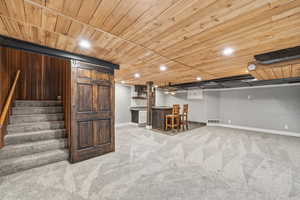 Finished below grade area with a bar, wooden ceiling, light colored carpet, and recessed lighting