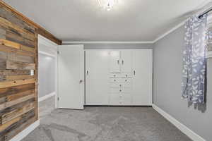 Unfurnished bedroom featuring light carpet, a textured ceiling, a closet, and crown molding