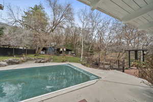 View of pool featuring a fenced backyard, patio surround, and an outbuilding