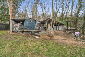 View of front facade featuring a wooden deck, an outdoor structure, a front yard, and a garage