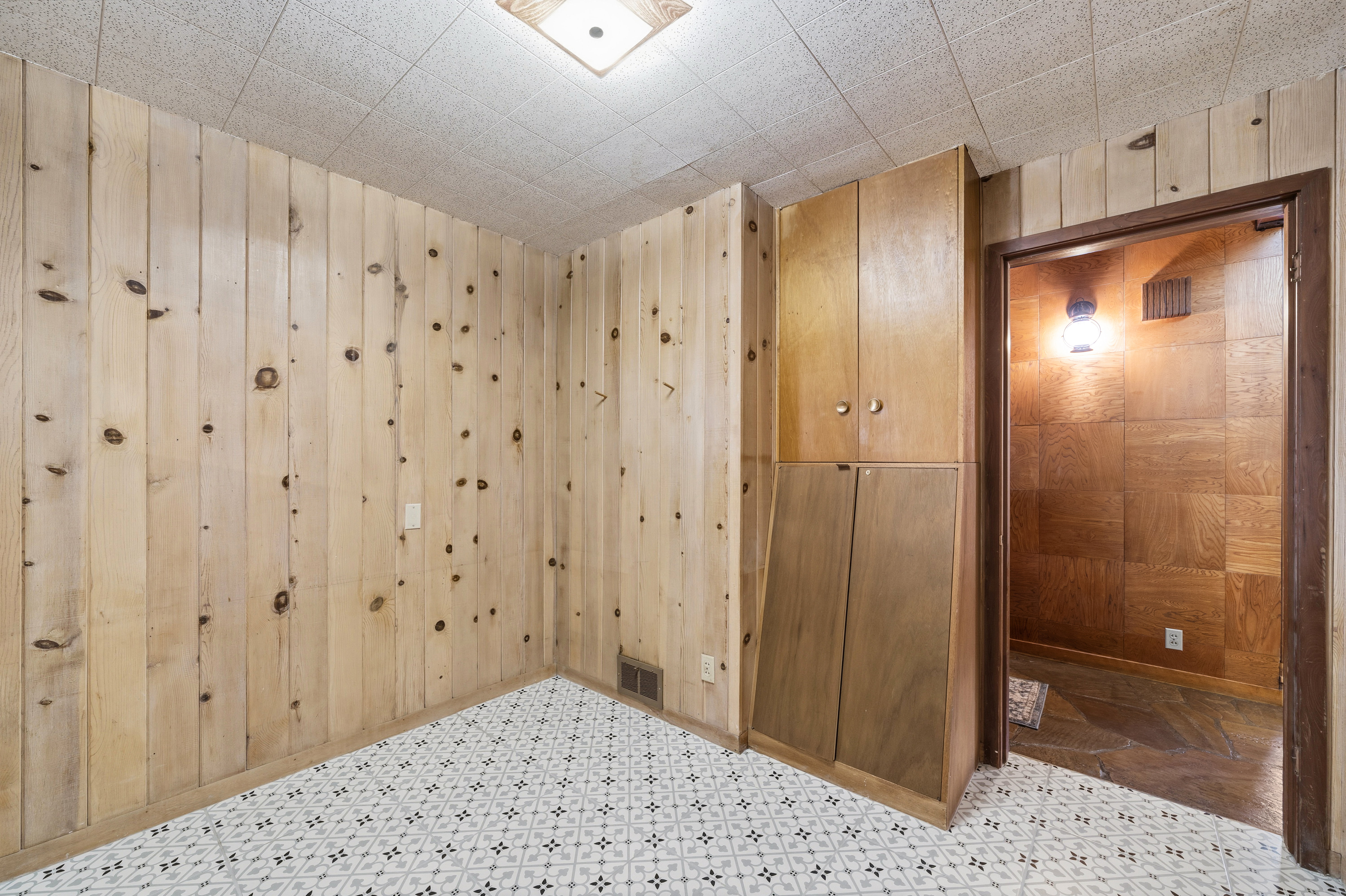 Unfurnished room featuring wood walls and tile patterned floors