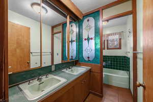 Bathroom with a bath, a textured ceiling, tile patterned flooring, and double vanity
