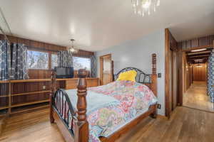 Bedroom with wooden walls, a chandelier, and hardwood / wood-style flooring