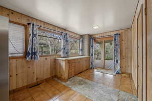 Interior space with light tile patterned flooring, wooden walls, and vanity