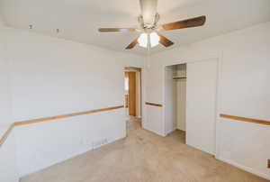 Unfurnished bedroom featuring light carpet, a closet, and a ceiling fan