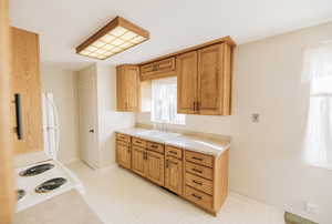 Kitchen featuring light countertops, light floors, white appliances, and wood finish cabinets