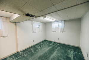 Basement with dark carpet and a paneled ceiling