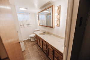 Full bath featuring vanity, dark tile patterned flooring, and a stall shower