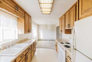 Kitchen with white appliances, light countertops, a chandelier, light colored carpet, and light floors