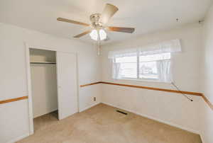 Unfurnished bedroom with light carpet, a closet, and a ceiling fan