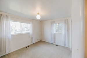 Spare room featuring light colored carpet and baseboards