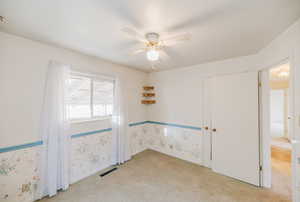Unfurnished room with a ceiling fan, light carpet, and wallpapered walls