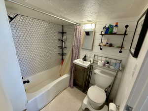 Full bathroom with a textured ceiling, vanity, and shower / bath combo