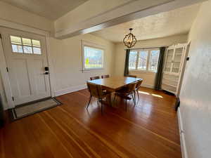 Dining space with a textured ceiling, a textured wall, hardwood / wood-style flooring, and a chandelier