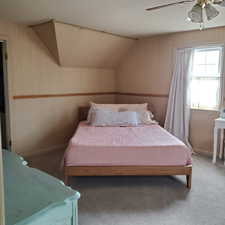 Bedroom featuring wallpapered walls, carpet flooring, lofted ceiling, and a ceiling fan