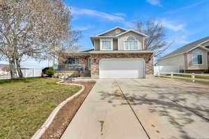 Traditional-style house featuring brick siding, concrete driveway, a garage, and covered porch