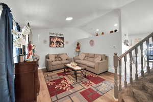 Living area featuring light wood-style flooring, vaulted ceiling, and recessed lighting