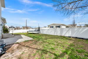 Fenced backyard with a trampoline, a patio area, and a residential view