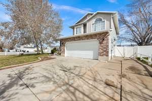 View of front facade featuring a gate, driveway, an attached garage, and brick siding