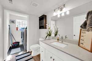 Half bathroom with separate washer and dryer, vanity, and light wood-style floors