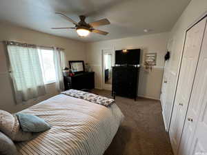 Carpeted bedroom with ceiling fan and a closet