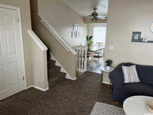 Living room with a ceiling fan, lofted ceiling, and dark colored carpet