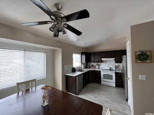 Kitchen with light countertops, stainless steel appliances, dark wood finish cabinetry, tasteful backsplash, and vaulted ceiling