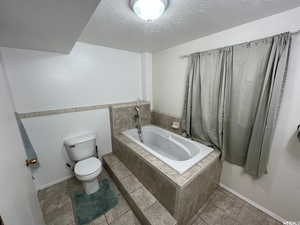 Full bathroom with a tub with jets and a textured ceiling