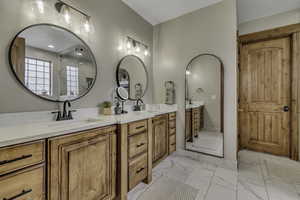Full bathroom with double vanity, light marble finish flooring, and a marble finish shower