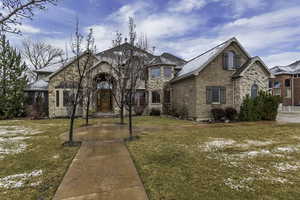 View of front facade with brick siding, a front lawn, and stone siding