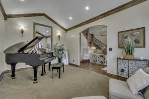 Sitting room with arched walkways, crown molding, lofted ceiling, carpet flooring, and recessed lighting