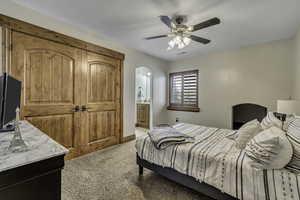 Bedroom with light carpet, a ceiling fan, and ensuite bathroom