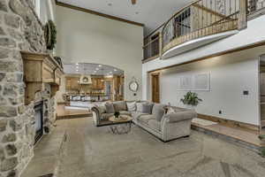 Living room with a fireplace, a high ceiling, crown molding, and recessed lighting