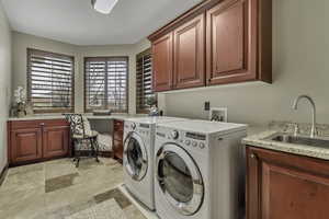 Laundry room with healthy amount of natural light, independent washer and dryer, cabinet space, and light stone finish flooring